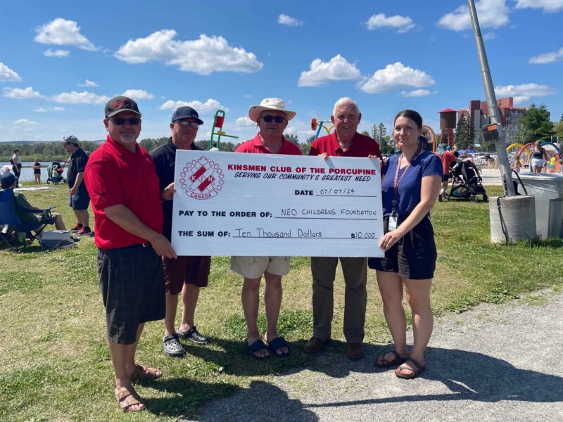 Group of people outside holding a large cheque